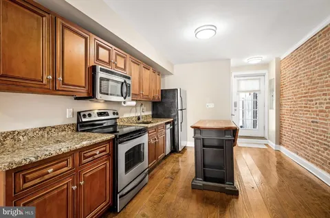 a kitchen with stainless steel appliances granite countertop wooden cabinets a stove top oven a sink and dishwasher
