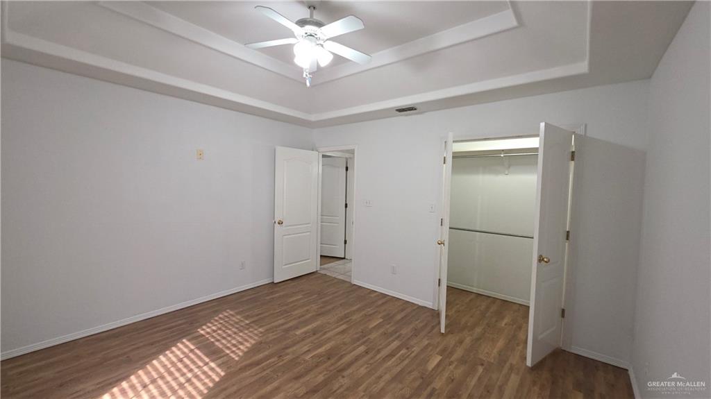 2014 Northgate Circle Weslaco, TX 78599 - Photo 11 of 23 Unfurnished bedroom featuring a tray ceiling, dark wood-style floors, a spacious closet, and ceiling fan