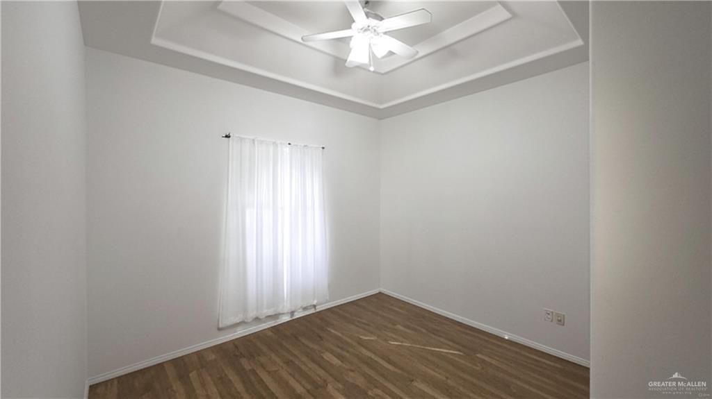 2014 Northgate Circle Weslaco, TX 78599 - Photo 13 of 23 Spare room featuring a tray ceiling, ceiling fan, and dark wood-type flooring
