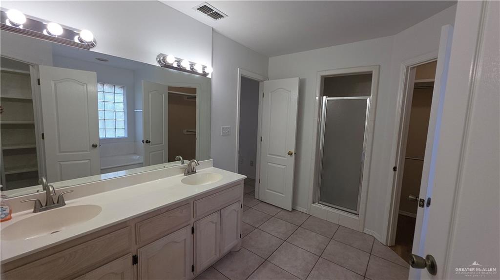 2014 Northgate Circle Weslaco, TX 78599 - Photo 17 of 23 Bathroom with a walk in closet, a stall shower, double vanity, light tile patterned floors, and a garden tub