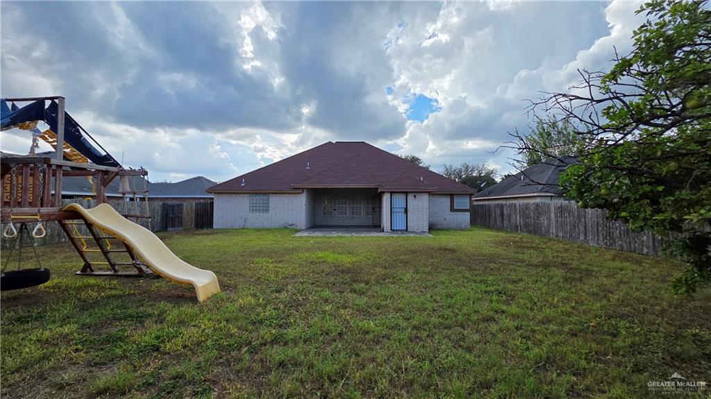 2014 Northgate Circle Weslaco, TX 78599 - Photo 22 of 23 Rear view of property featuring a playground, a fenced backyard, a patio, and brick siding