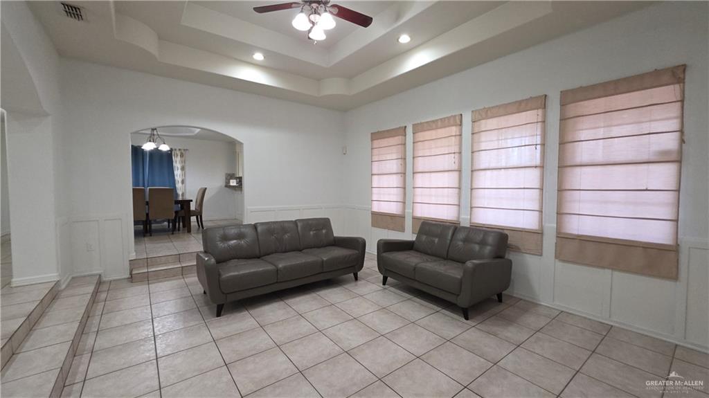 2014 Northgate Circle Weslaco, TX 78599 - Photo 6 of 23 Living area with light tile patterned floors, a chandelier, a tray ceiling, wainscoting, and arched walkways