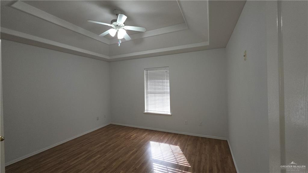 2014 Northgate Circle Weslaco, TX 78599 - Photo 10 of 23 Unfurnished room with a tray ceiling, dark wood finished floors, and ceiling fan