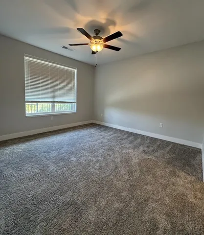 a view of an empty room and chandelier fan