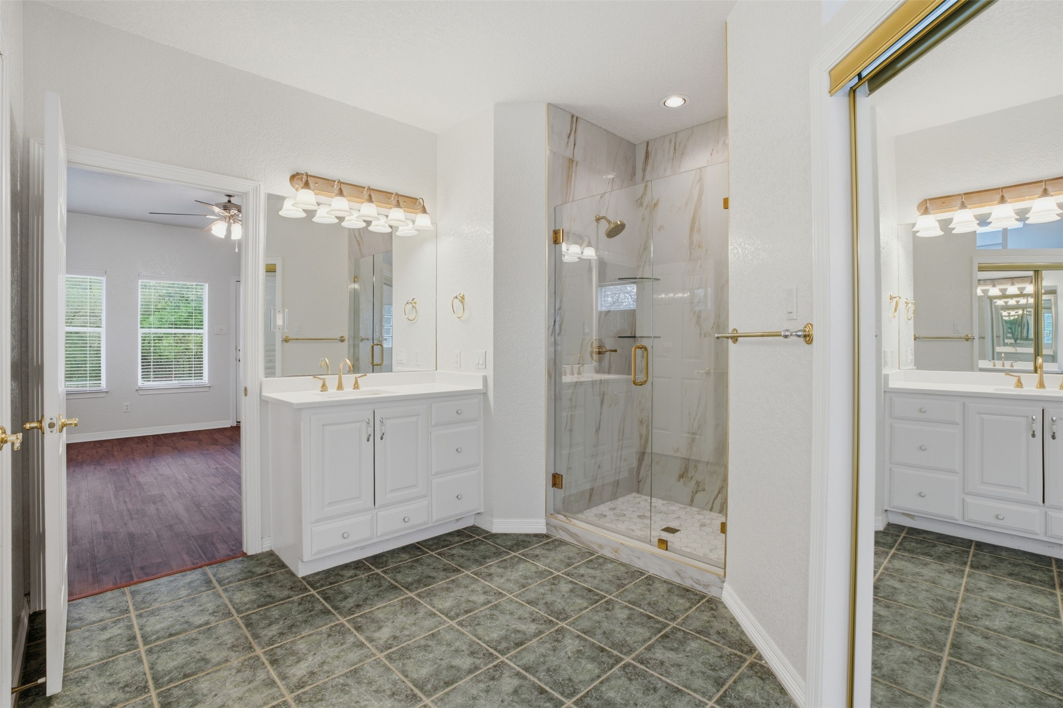 1301 County Road 262 Georgetown, TX 78633 - Photo 19 of 39 Bathroom featuring a glass-enclosed shower with tile surround, dual white vanities with gold-toned fixtures, and square floor tiles