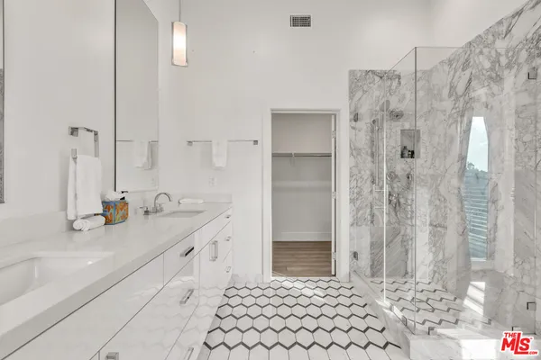 a bathroom with a granite countertop sink a mirror and shower