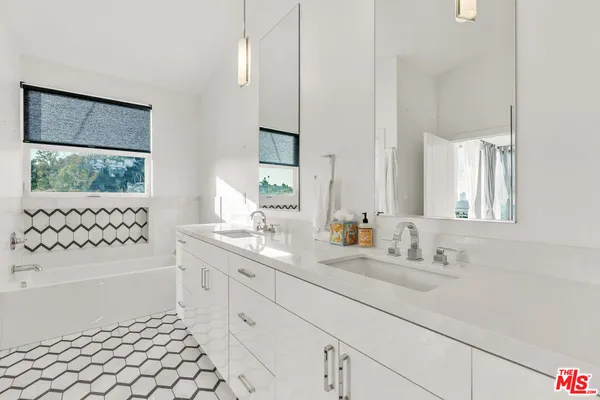 a bathroom with a sink a toilet a mirror a window and shower