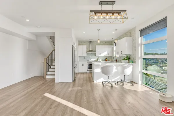 a living room with stainless steel appliances furniture a rug kitchen view and a chandelier