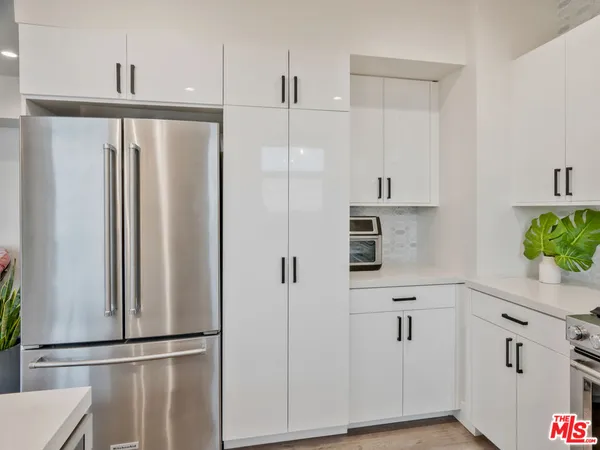 a kitchen with stainless steel appliances a refrigerator and a hard wood floor