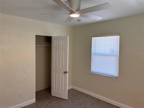 an empty room with windows and fan