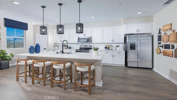 a kitchen with stainless steel appliances kitchen island granite countertop a sink a stove a refrigerator and island with wooden floor