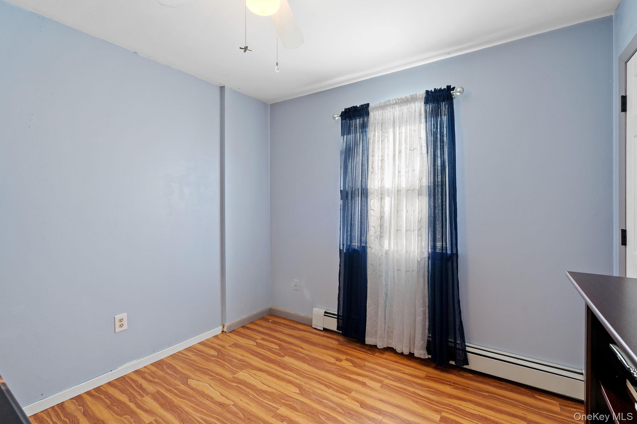 171 E Road Wallkill, NY 12589 - Photo 18 of 47 Unfurnished room with a baseboard heating unit, light wood finished floors, and ceiling fan