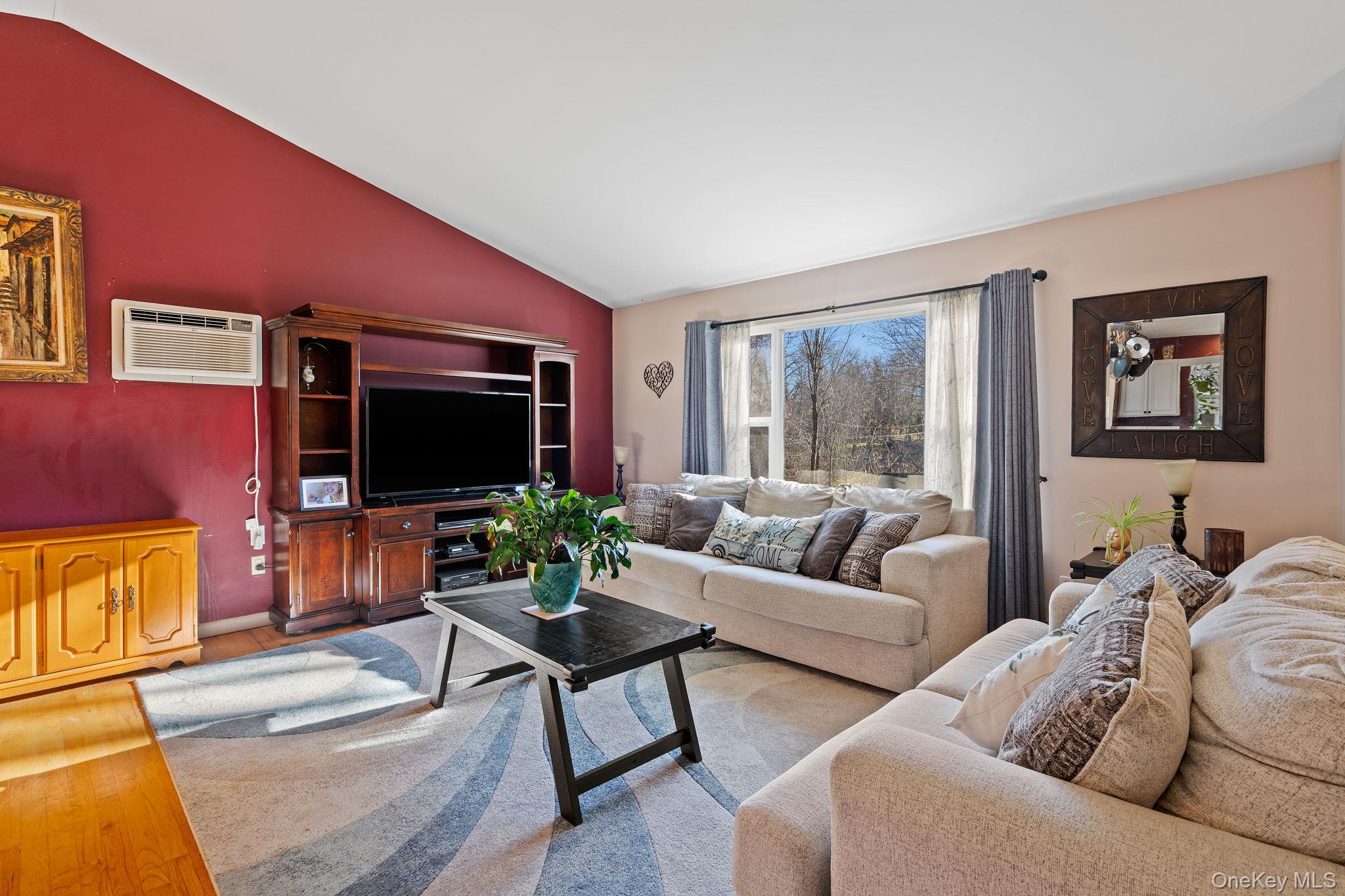 171 E Road Wallkill, NY 12589 - Photo 9 of 47 Living area with vaulted ceiling, a wall mounted air conditioner, and wood finished floors