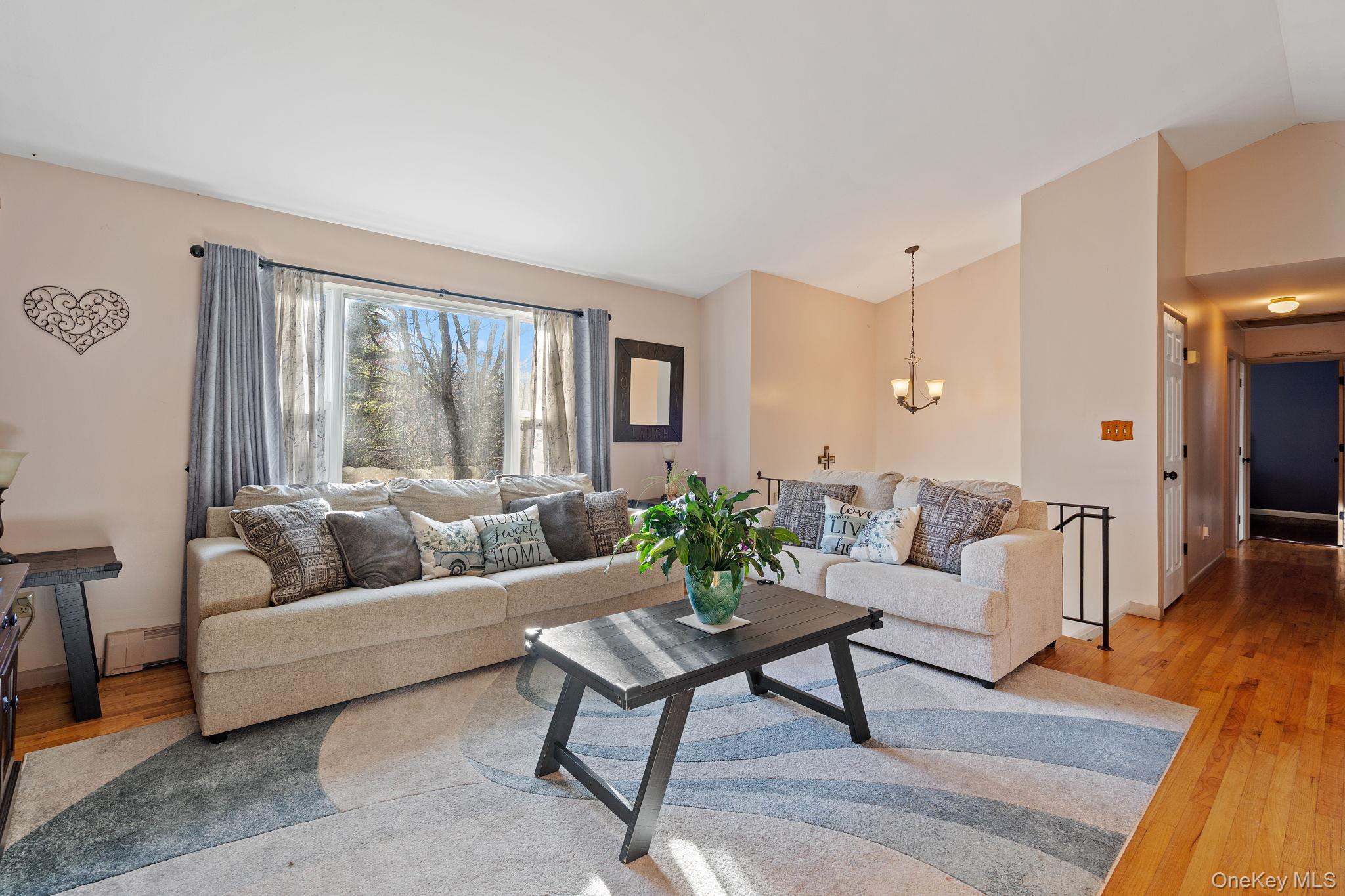 171 E Road Wallkill, NY 12589 - Photo 10 of 47 Living room featuring light wood-type flooring, vaulted ceiling, a chandelier, and a baseboard radiator