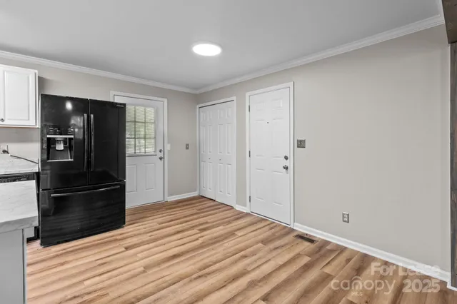 a view of a livingroom with wooden floor and kitchen appliances