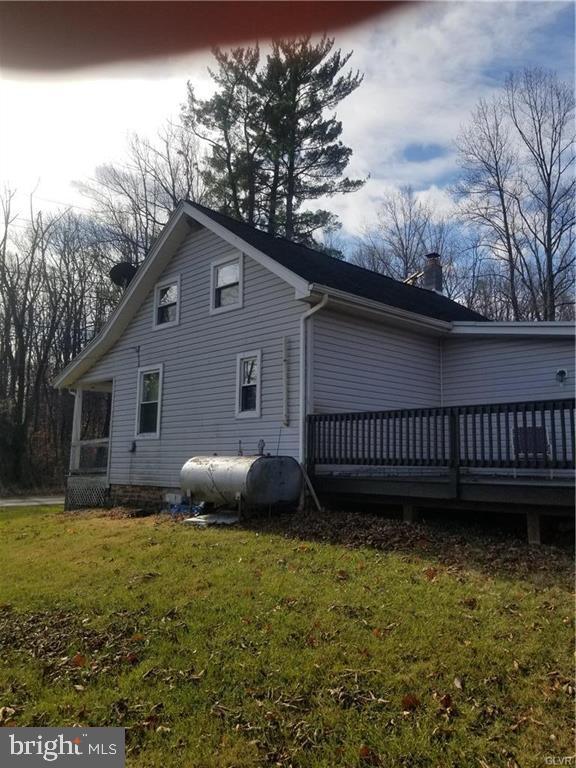 107 Rock Ridge Road Ottsville, PA 18942 - Photo 4 of 10 a view of a house with a yard plants and a large tree