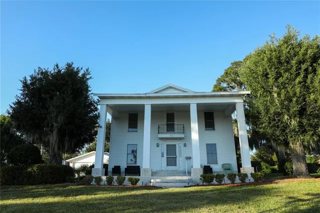 a front view of a house with a garden and trees