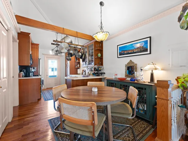 a dining room with wooden floor a chandelier a wooden table and chairs