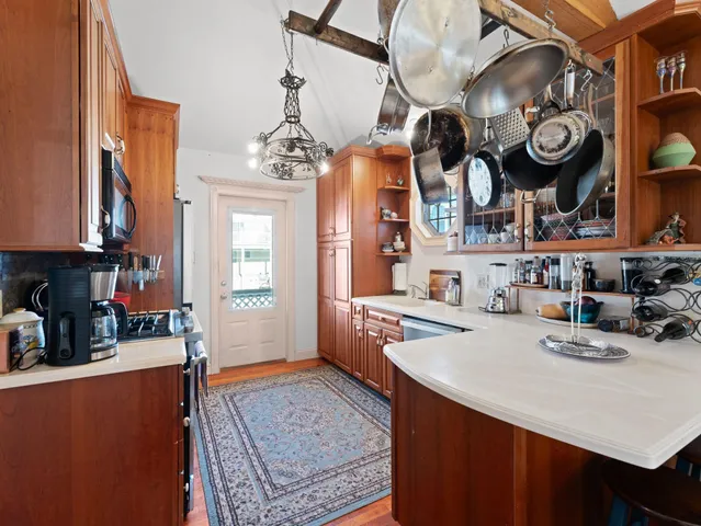 a very nice looking open kitchen with stainless steel appliances granite countertop a stove a sink a dining table and chairs with wooden floor