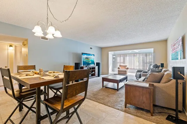 a living room with furniture a chandelier and a dining table