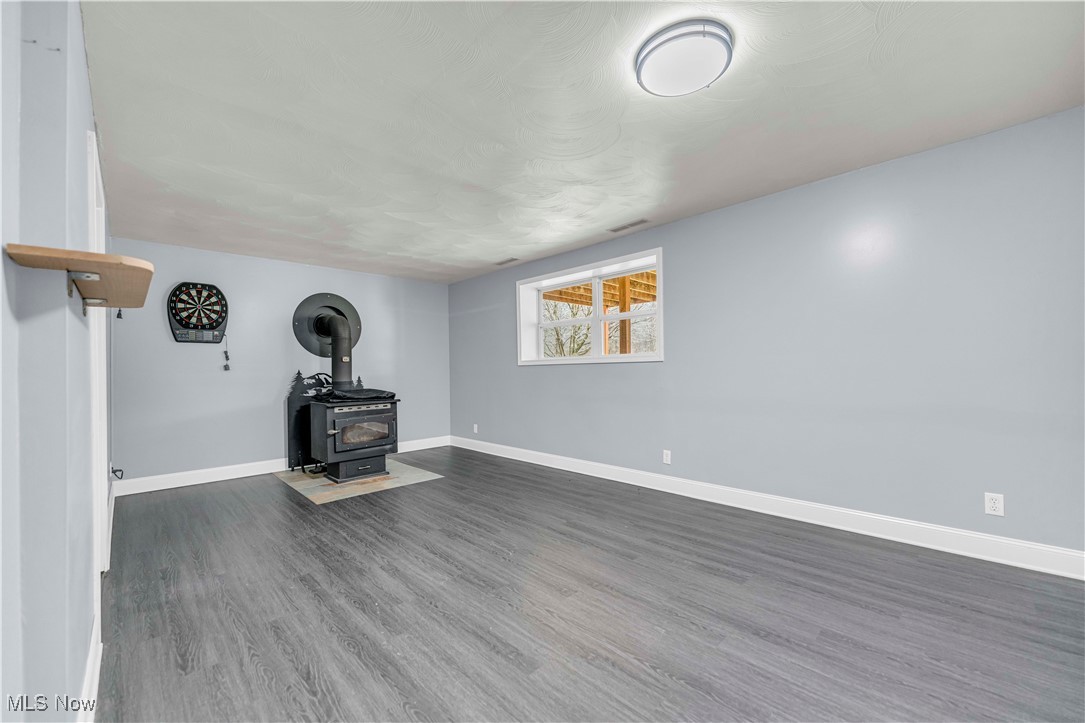 8110 Risden Road Vermilion, OH 44089 - Photo 18 of 48 Unfurnished living room with dark hardwood / wood-style flooring and a wood stove
