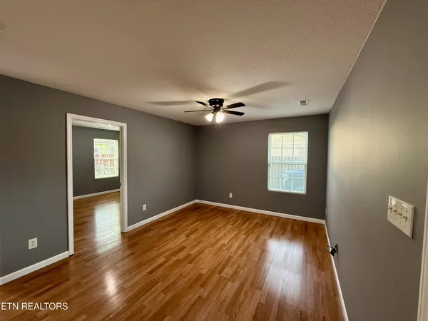 a view of an empty room with wooden floor and a window