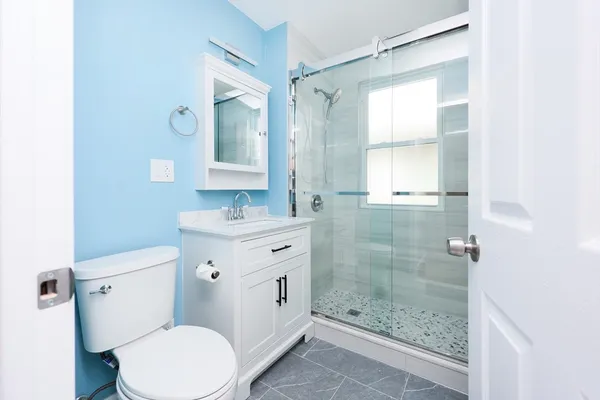 a bathroom with a granite countertop toilet a sink and a mirror