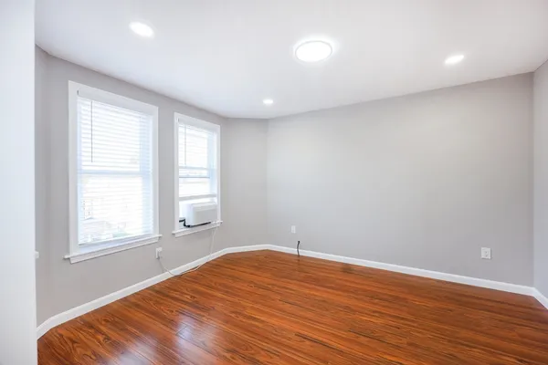 an empty room with wooden floor and windows