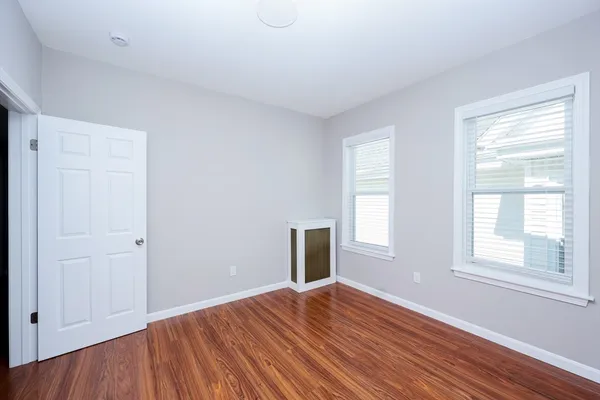 an empty room with wooden floor cabinet and windows