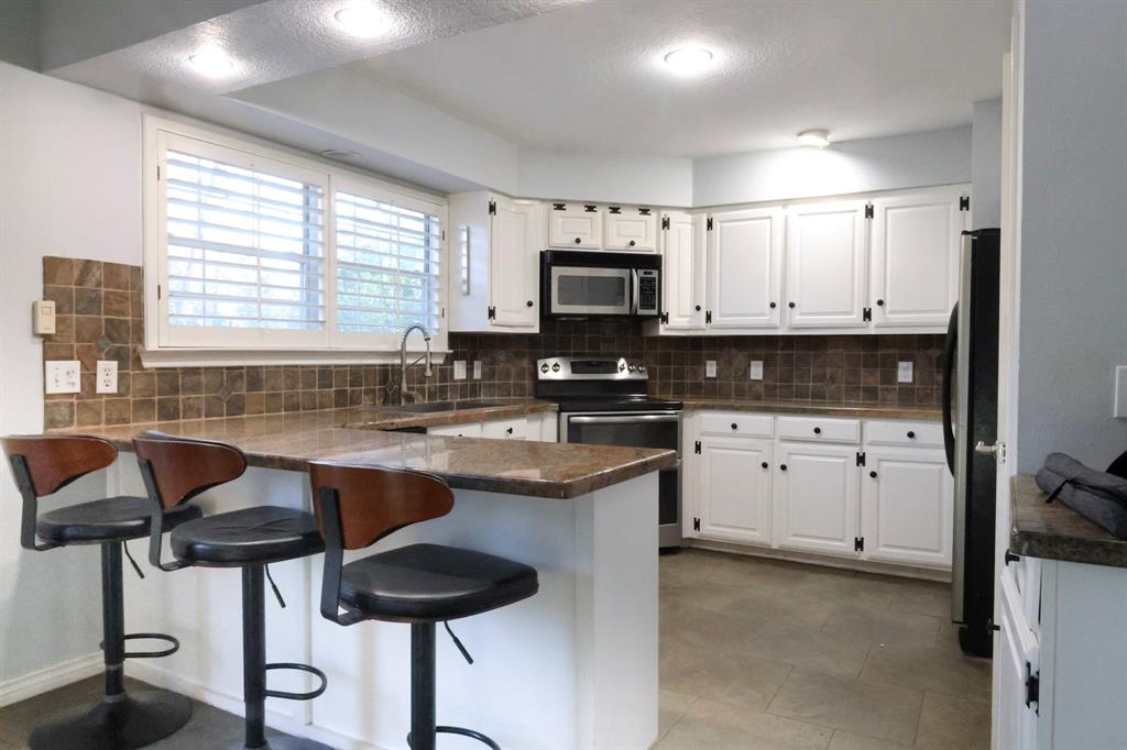 740 Peavy Road Dallas, TX 75218 - Photo 5 of 19 a kitchen with stainless steel appliances granite countertop a stove top oven a sink a counter space and cabinets