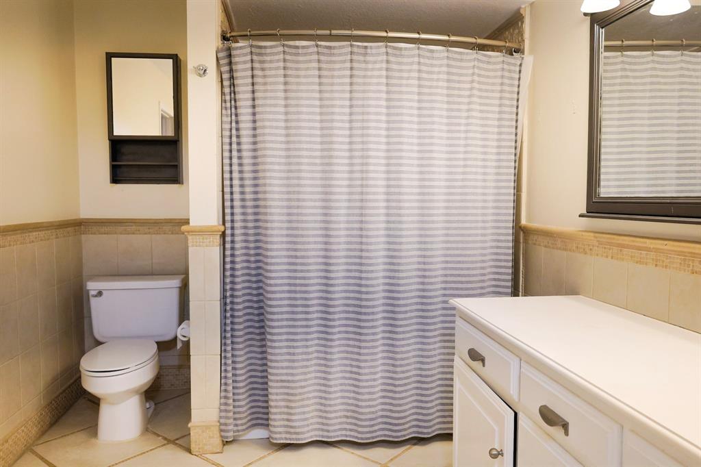 740 Peavy Road Dallas, TX 75218 - Photo 10 of 19 a bathroom with a toilet and a shower curtain