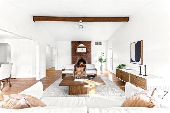 2481 West Rebecca Way Meridian, ID 83646 - Photo 10 of 17 Living room featuring wood finished floors, vaulted ceiling with beams, a fireplace, ceiling fan, and arched walkways