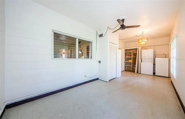 an empty room with windows and chandelier fan