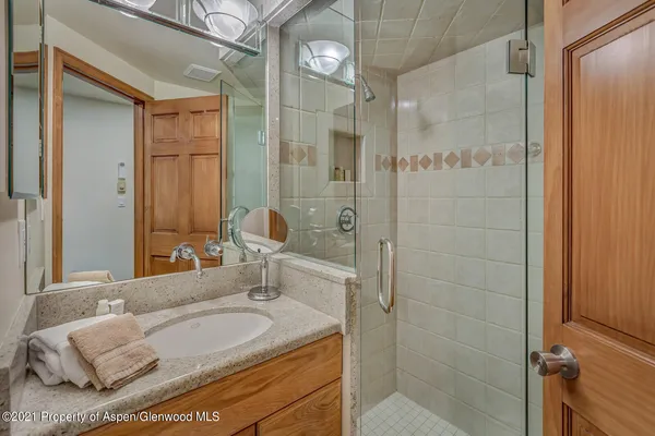 a bathroom with a granite countertop sink a mirror and a shower