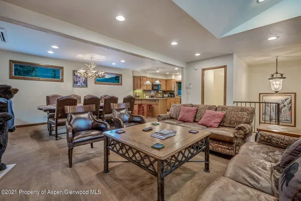 a living room with furniture potted plant and kitchen view