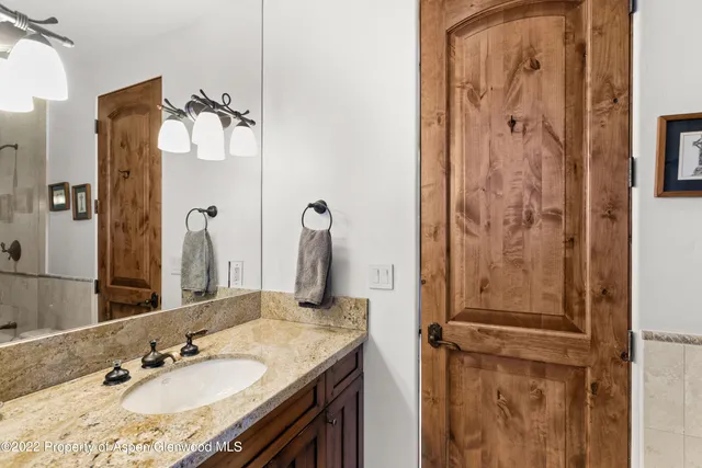 a bathroom with a granite countertop sink and a mirror
