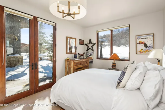 a bedroom with a large bed and a large window with the outer view