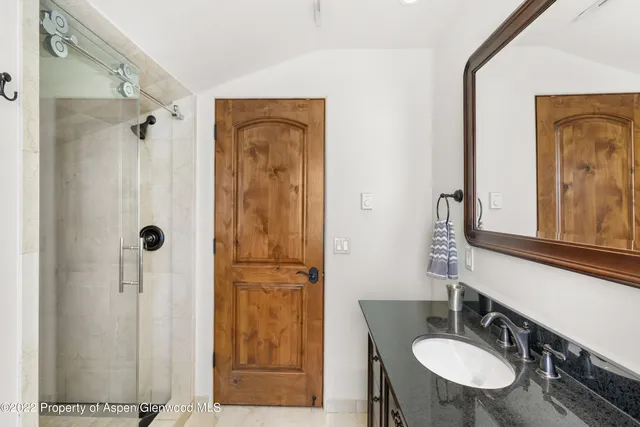 a bathroom with a sink a mirror a glass door a shower and a mirror