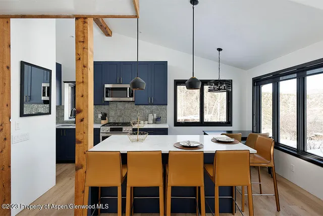 a kitchen with stainless steel appliances granite countertop a stove a sink a microwave a dining table and chairs with wooden floor