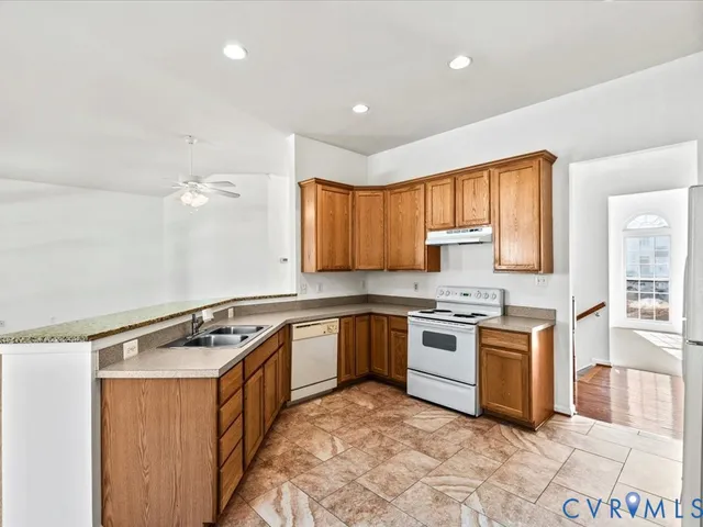 a kitchen with stainless steel appliances granite countertop a stove a sink dishwasher and a refrigerator