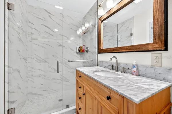 a bathroom with a granite countertop sink vanity mirror and shower