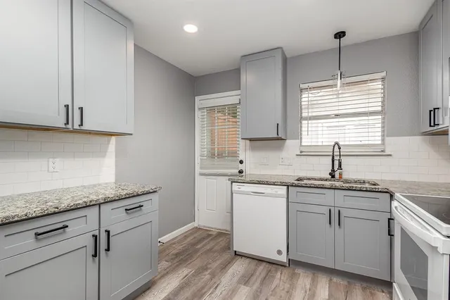 a kitchen with a sink cabinets wooden floor and a window
