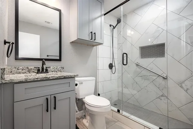 a bathroom with a granite countertop sink toilet and shower
