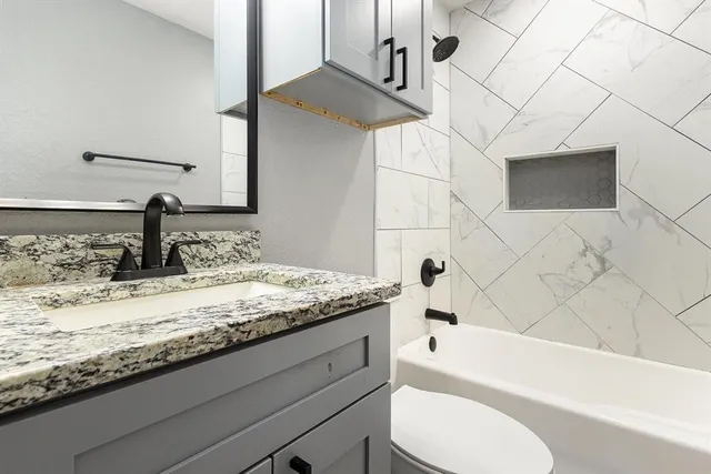 a bathroom with a granite countertop sink toilet and bathtub