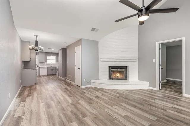 a view of a big room with wooden floor a ceiling fan and a kitchen
