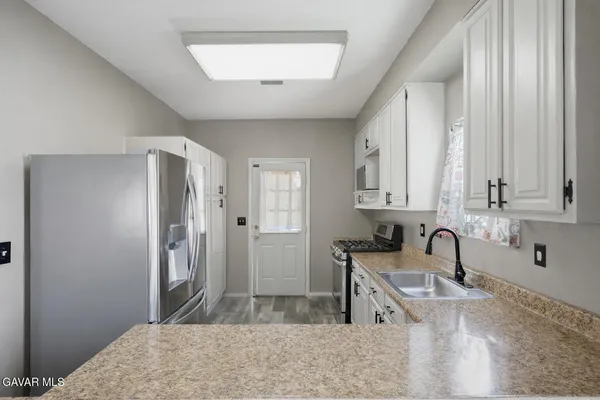 a kitchen with stainless steel appliances granite countertop a sink refrigerator and cabinets