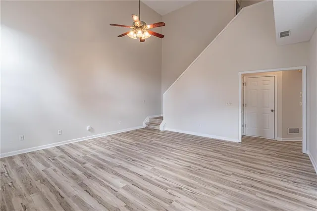 a view of empty room with wooden floor and ceiling fan