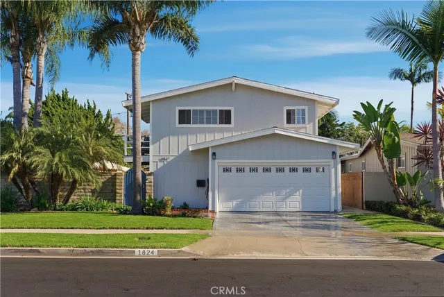 a front view of a house with a garden and palm trees