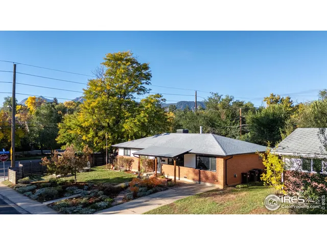 a backyard of a house with table and chairs under an umbrella