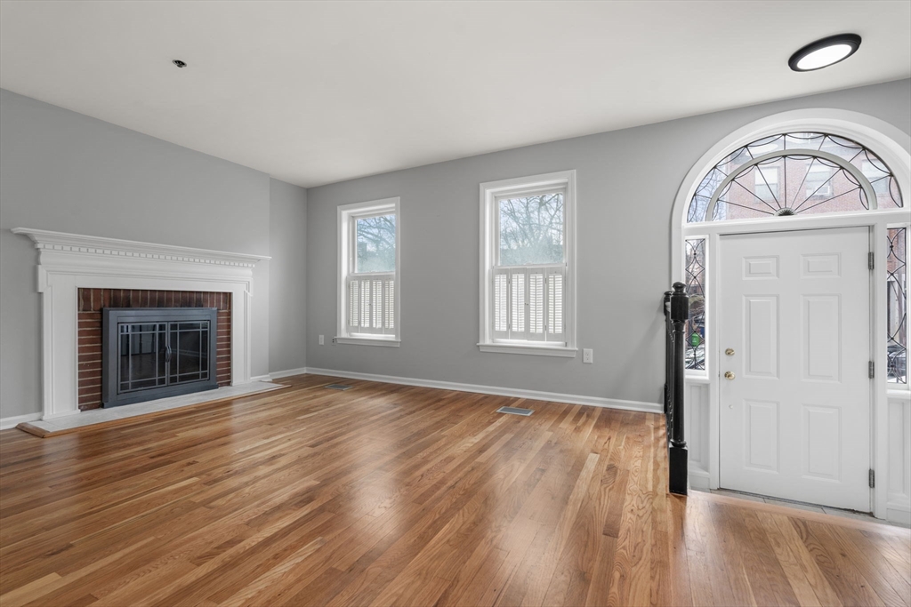 5 Main Street, Unit 5 Boston, MA 02129 - Photo 6 of 19 an empty room with wooden floor a fireplace and windows